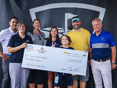 Musket and Trillium employees giving big check to Texas Childrens Hospital at golf tournament with patient and father