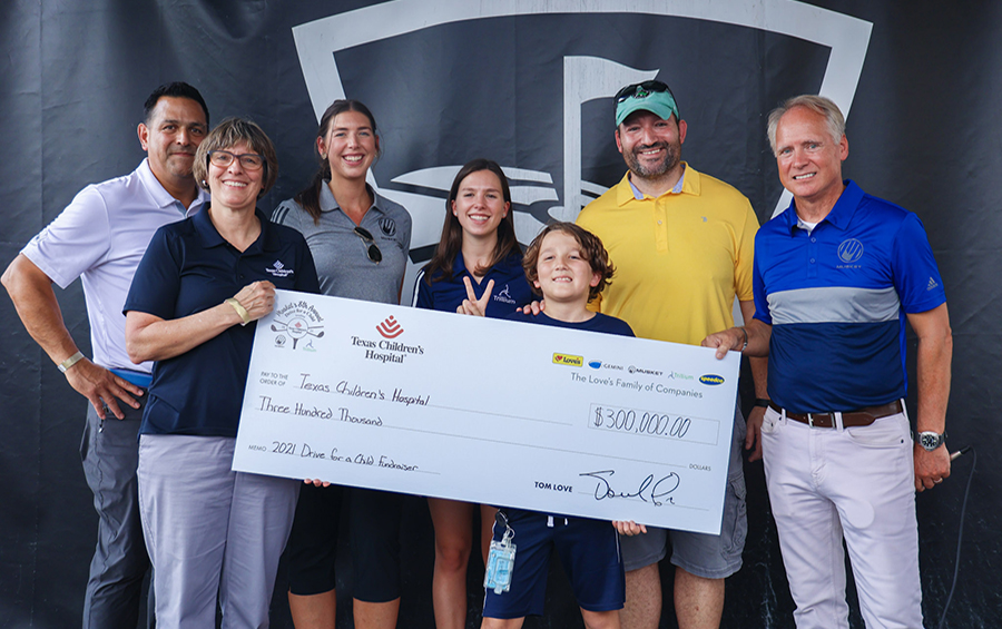 Musket and Trillium employees giving big check to Texas Childrens Hospital at golf tournament with patient and father