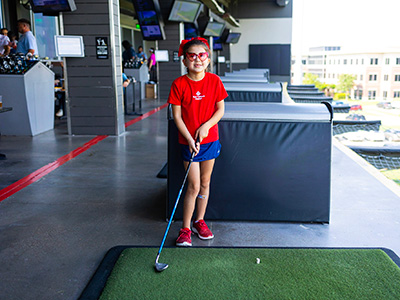 Little girl holding a golf club in a golfing bay. 